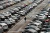File photo of an employee walking past new cars at the parking lot of Changan Ford Mazda Automobile Co. Ltd, Ford Motor's joint venture in China, in Chongqing Municipality
