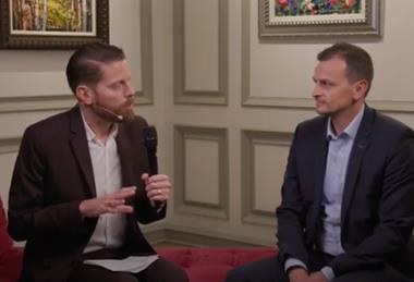 Gabriel Mair sits with Christopher Ludwig on a red sofa for an interview