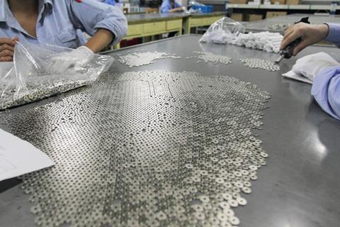 Workers prepare rare earth magnet components